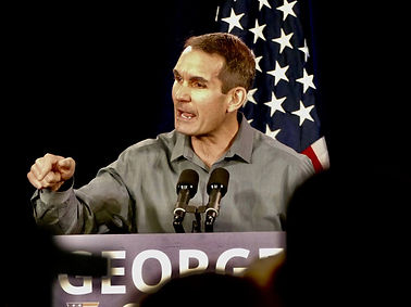 Eugene DePasquale speaking in front of the American flag, advocating for justice and transparency as PA Attorney General.